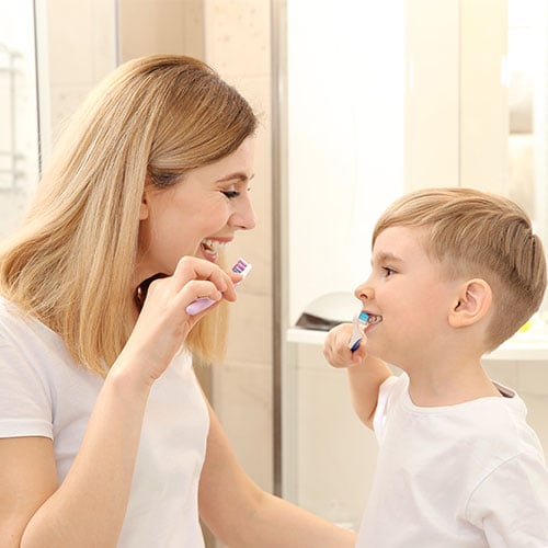 beautiful mother happy son brushing teeth